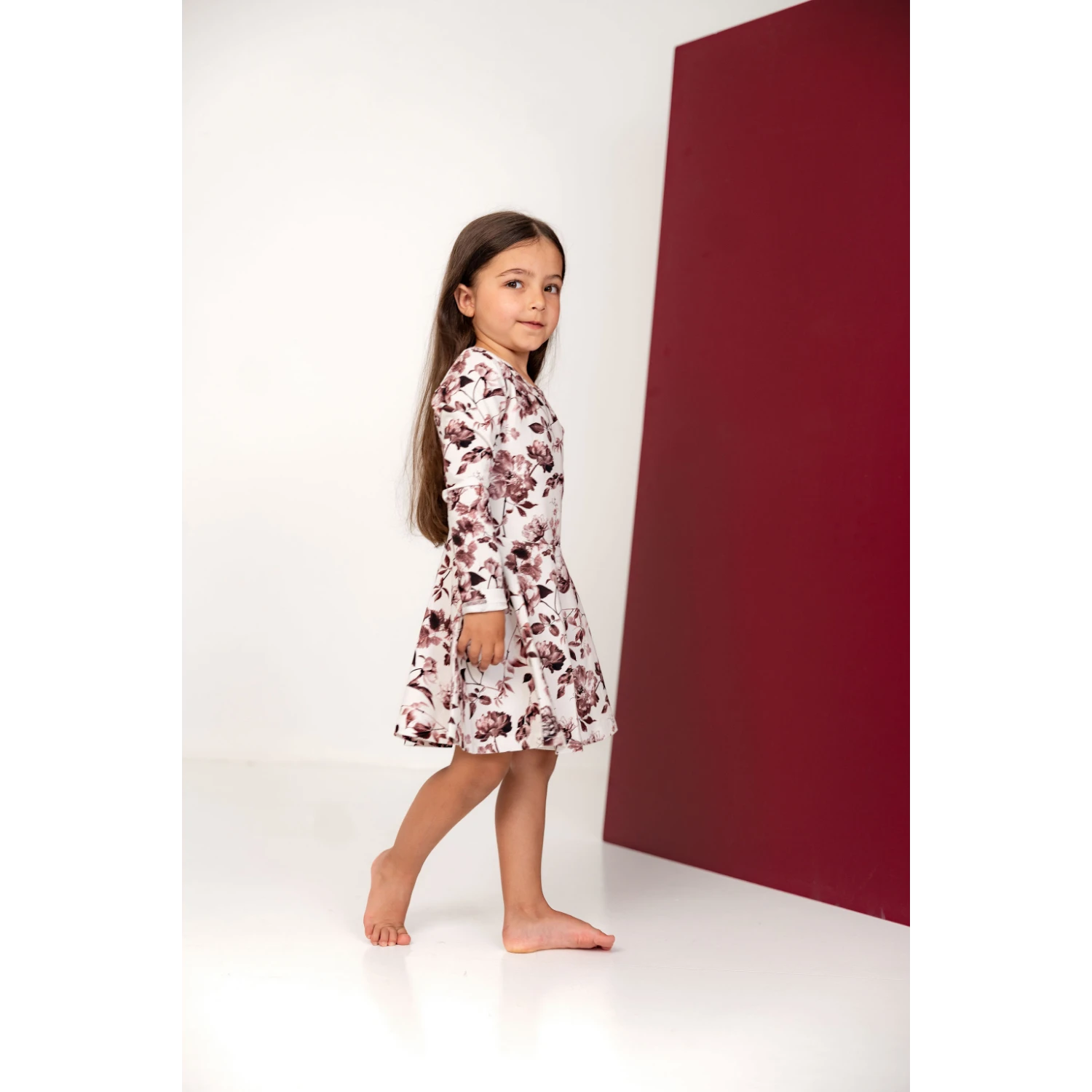 Tyttö katsoo kameraan päällään kaunis kukka kuosillinen mekko