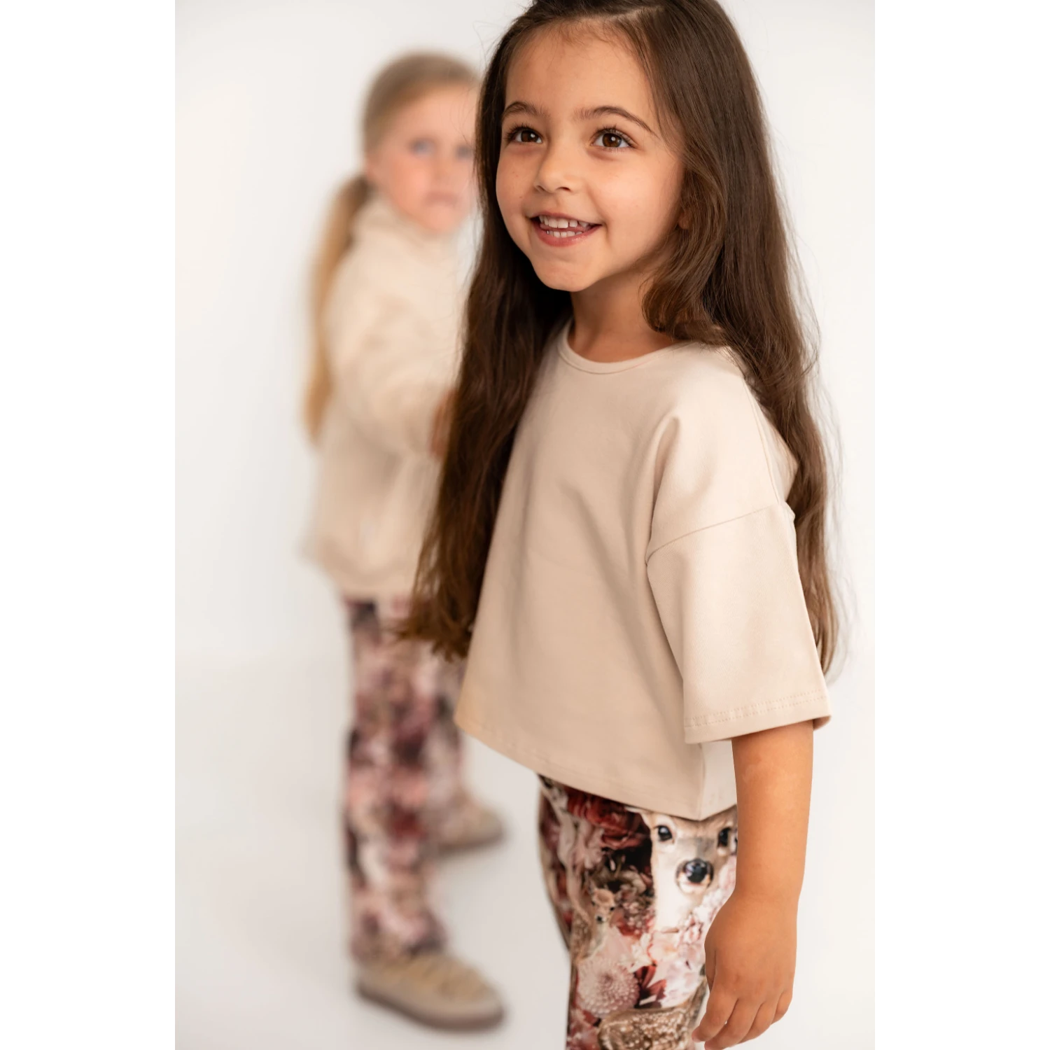 Tyttö hymyilee kameralle kaunis beige t-paita päällään.