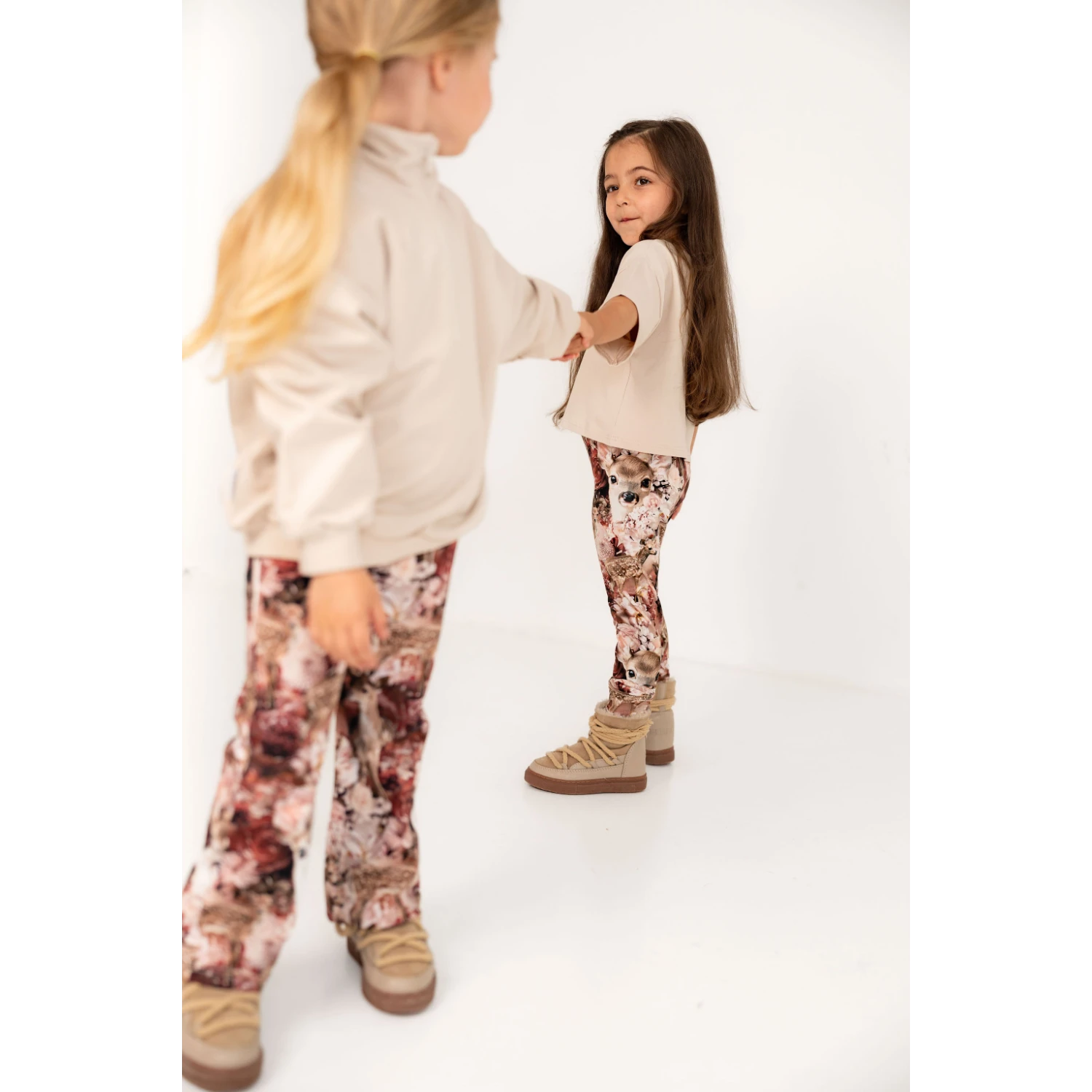 Kaksi tyttöä tanssimassa. Lapsilla on päällä beigeä ja bambi kukka kuosia.