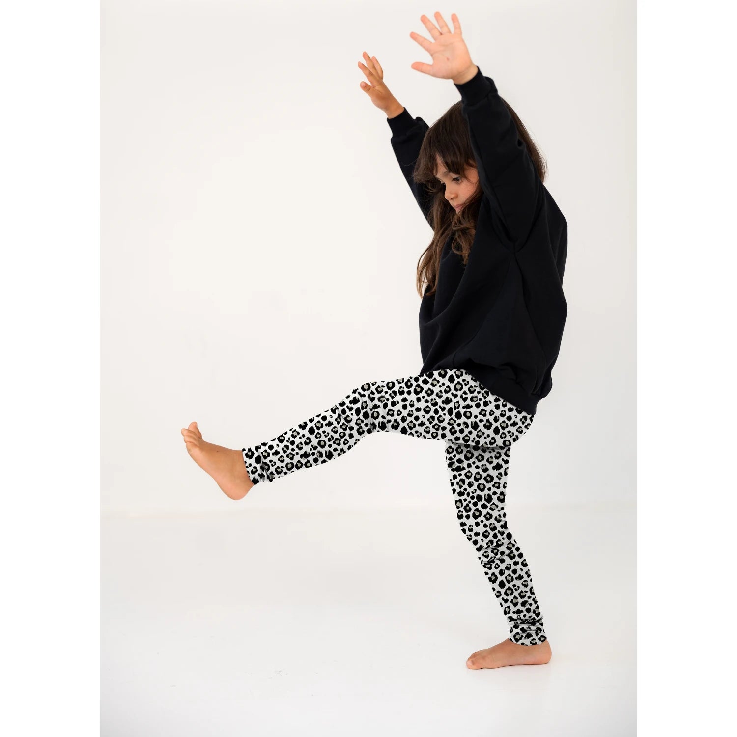 Tyttö mustassa paidassa ja Gugguu leopardi kuvioisissa leggingseissä. Juuri tekemässä kärrynpyörää