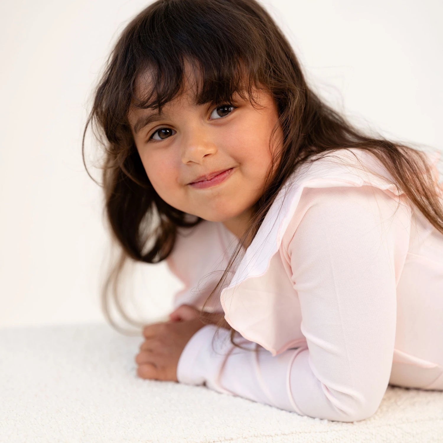 Tyttö lähikuvassa vaaleanpunaisessa frillamekossa – pehmeä ja iloinen tunnelma