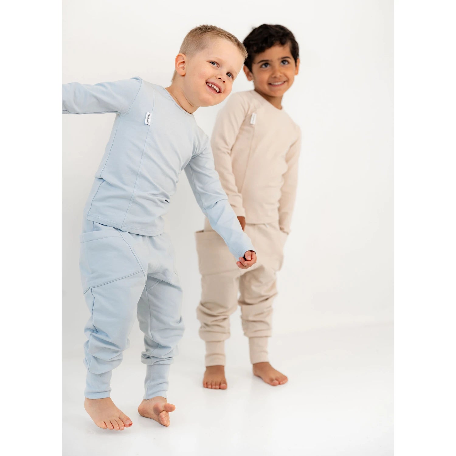 [ALL] Kaksi lasta seisoo vierekkäin, toinen vaaleansinisessä ja toinen beigessä setissä.